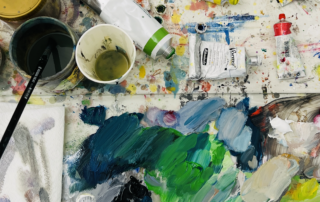 Buntes Maleratelier mit Farbpaletten, Pinseln und Farbtuben für professionelle Auftragsmalerei und individuelle Kunstwerke.