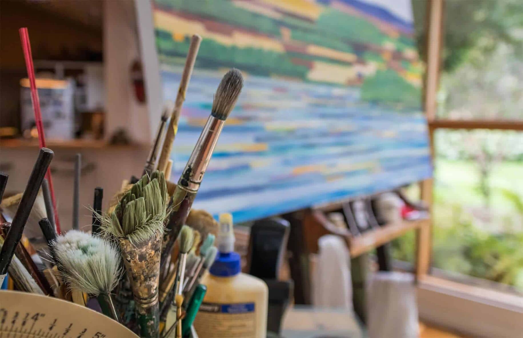 Farbfarbene Pinsel im Künstleratelier mit Gemälde im Hintergrund, kreative Malerei und Auftragsmalerei, Kunstwerke, Leinwand, Künstlerausrüstung, inspirierende Arbeitsumgebung, Nikolaus Kriese, professionelle Malerei.