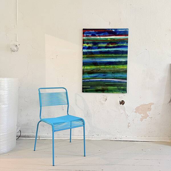 Farbenfrohes abstraktes Gemälde mit horizontalen Linien in Blau, Grün und Rot, an einer weißen Wand in einem Atelier.