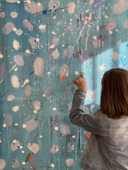 Farbenfrohe Abstrakte Malerei mit bunten Farbklecksen und Pinselstrichen, geschaffen von einem Kind beim Malen, in einem kreativen und inspirierenden Kunststudio.