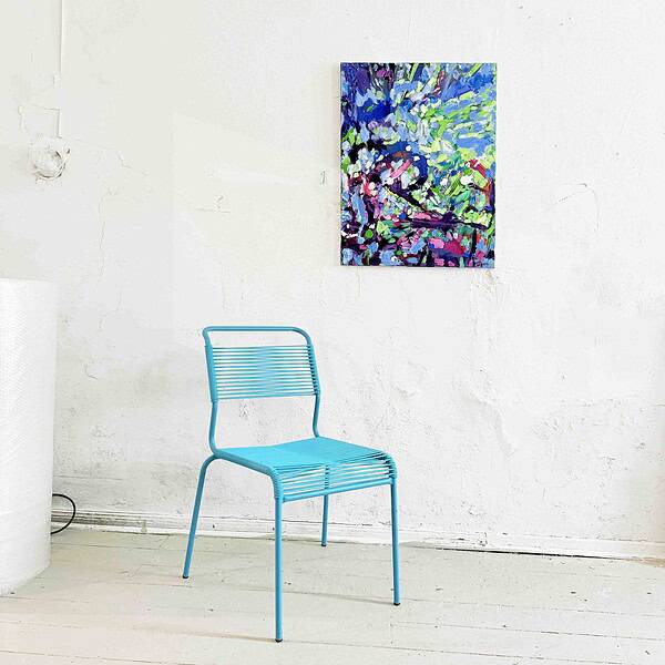 Lebendige abstrakte Acrylmalerei in einem Kunststudio mit blauer Sitzgelegenheit vor weißer Wand.