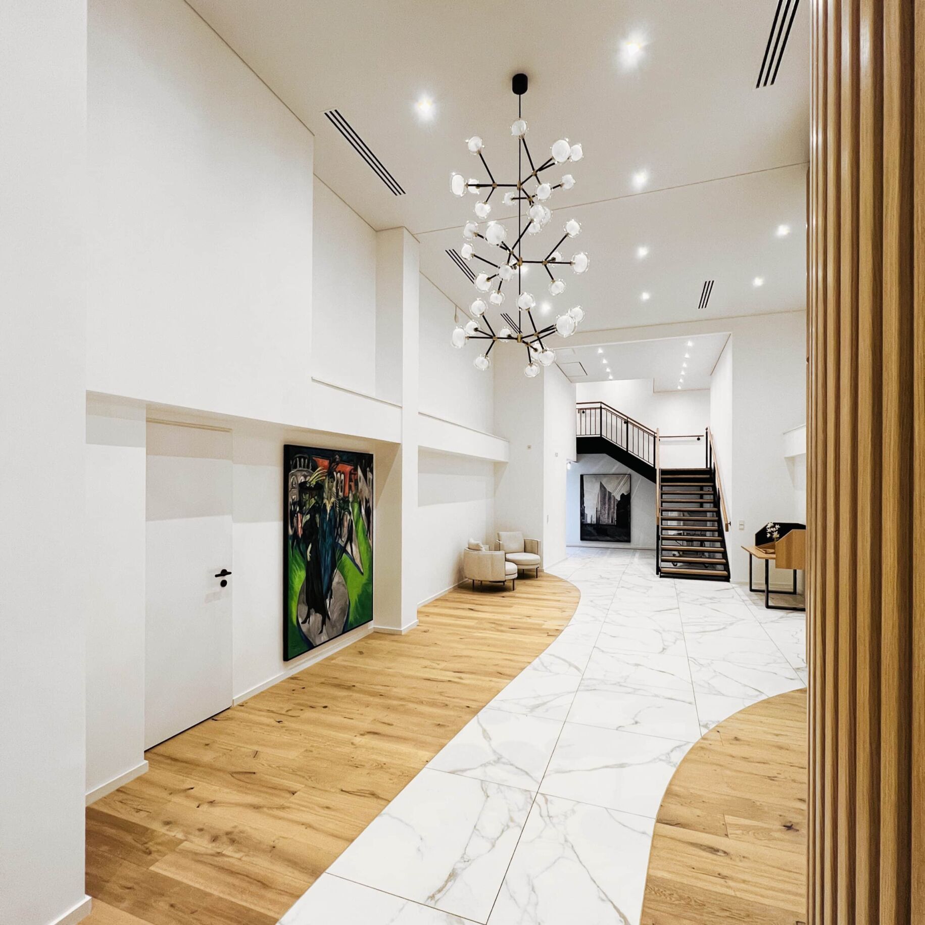Elegante Lobby mit moderner Kunst und stilvollem Design, weiße Wände, Holz- und Marmorelemente, großzügiger Raum, beeindruckender Kronleuchter, Gemälde vom Nikolaus Kriese nachmalen lassen.