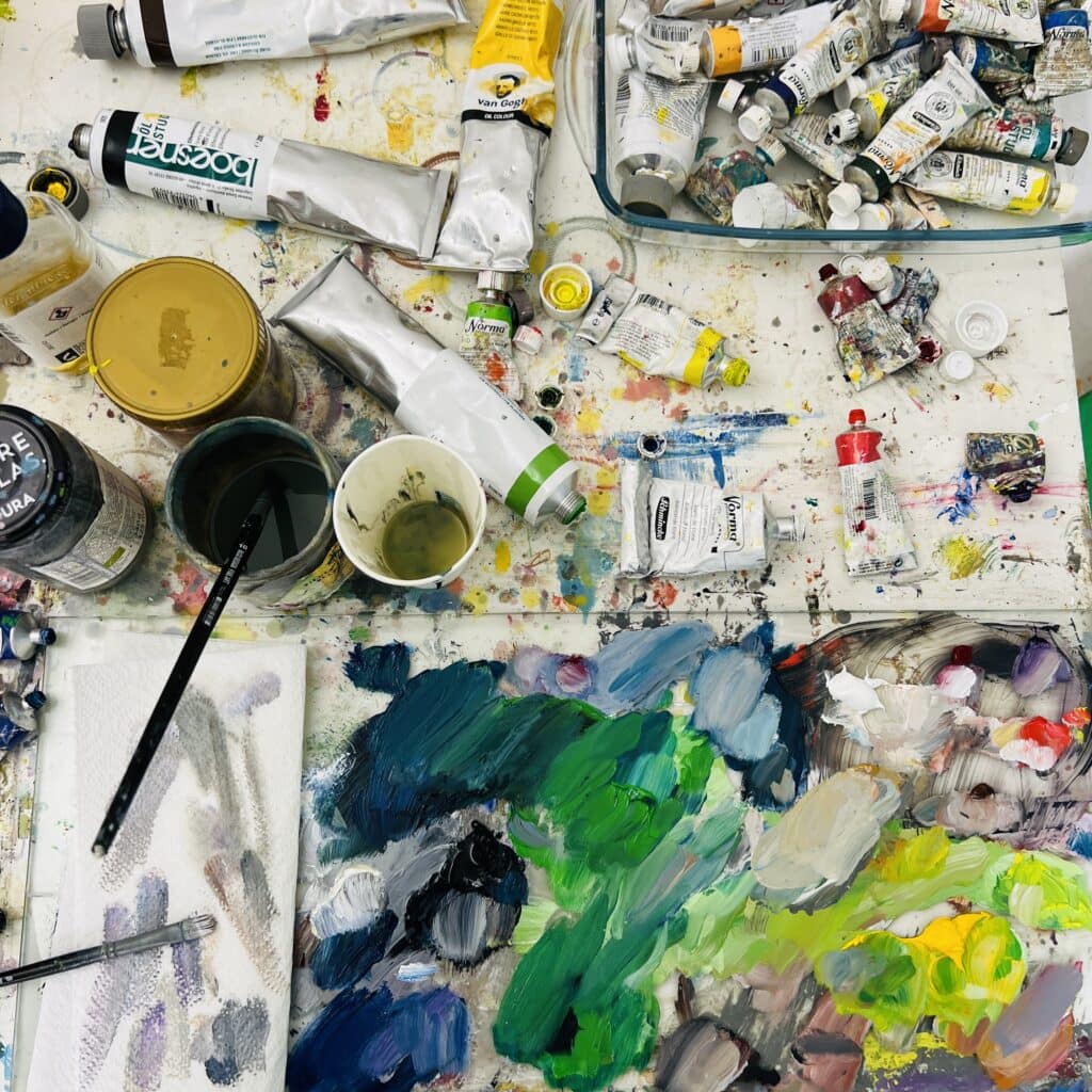 kunstkopie malen lassen im atelier nikolaus kriese deutschland Farben und Malutensilien auf einem Künstlerarbeitsplatz, Fokus auf kreative Malerei, Ölfarben, Acryl und Pinsel, ideal für Auftragsmalerei und künstlerische Werke.