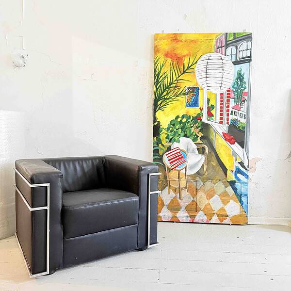 Farbenfrohes Stillleben mit einem bunten Kunstwerk, einem weißen Sessel und einer dezenten Hintergrundwand, ideal für individuelle Kunst- und Wohnraumgestaltung.