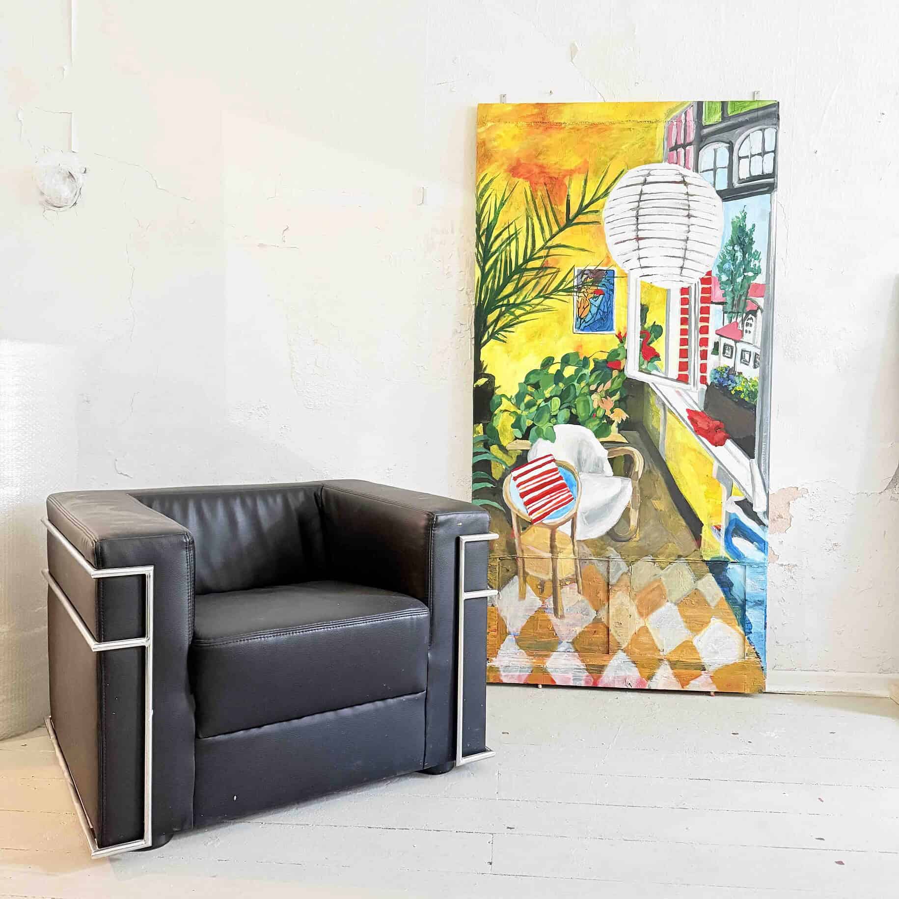 Farbenfrohes Stillleben mit einem bunten Kunstwerk, einem weißen Sessel und einer dezenten Hintergrundwand, ideal für individuelle Kunst- und Wohnraumgestaltung.