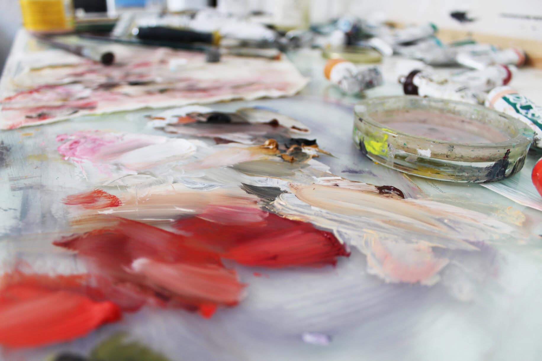 Bunte Malpalette mit verschiedenen Farben, Pinsel und Mischinstrumenten für professionelle Auftragsmalerei und kreative Kunstwerke.