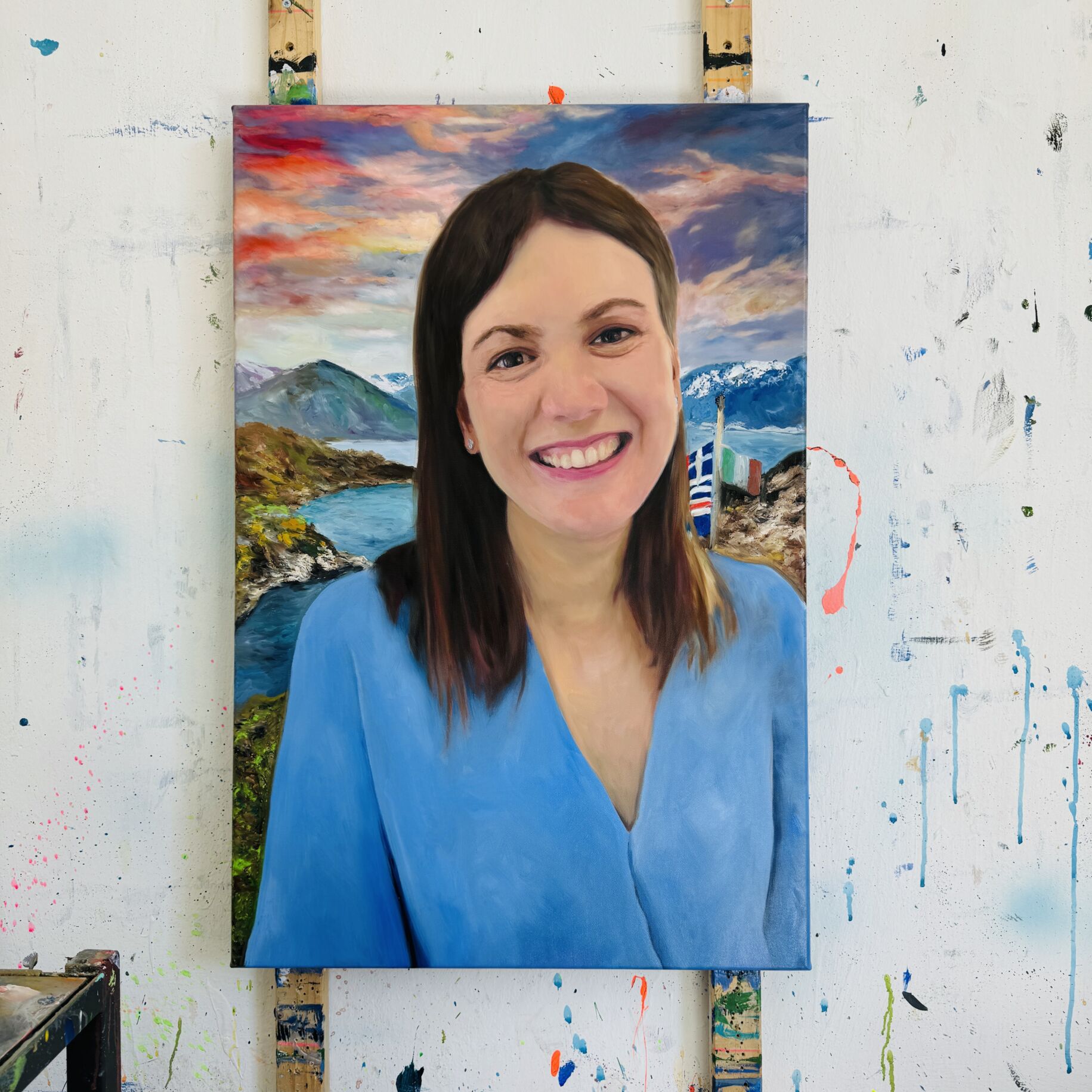 Bild von sich malen lassen Geschenk Porträt einer Frau im Atelier vor einer Landschaftsmalerei, Öl auf Leinwand, professionelle Auftragsmalerei, individuelle Portraits, kreative Künstlerarbeit, Kunstportrait.