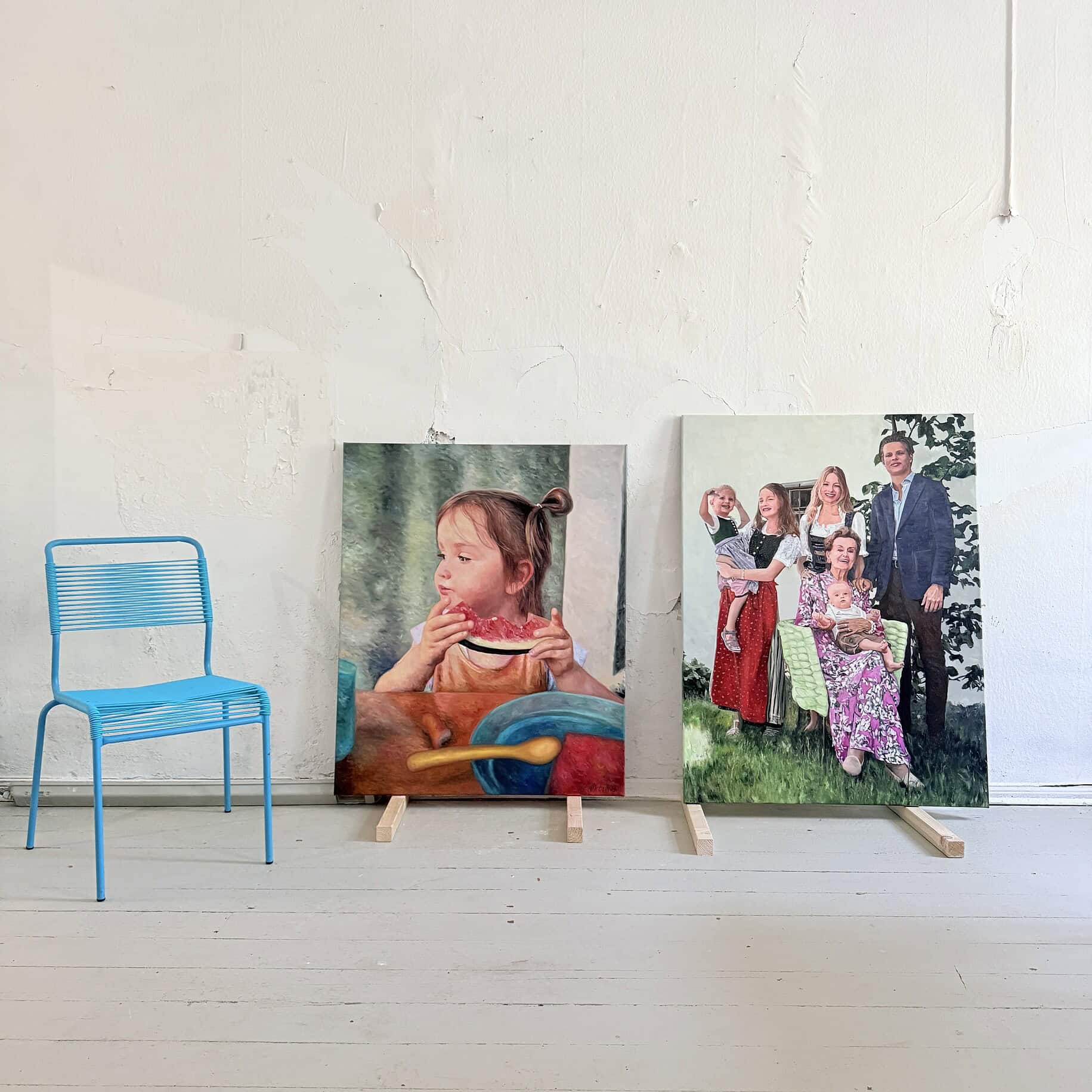 Portraitmalerei Familie mit Kindern Innenraum mit zwei realistischen Familienporträts auf Leinwand, einem kleinen blauen Metallstuhl, rustikalen weißen Boden und Wand, ideal für maßgeschneiderte Malerei- und Auftragskunst.