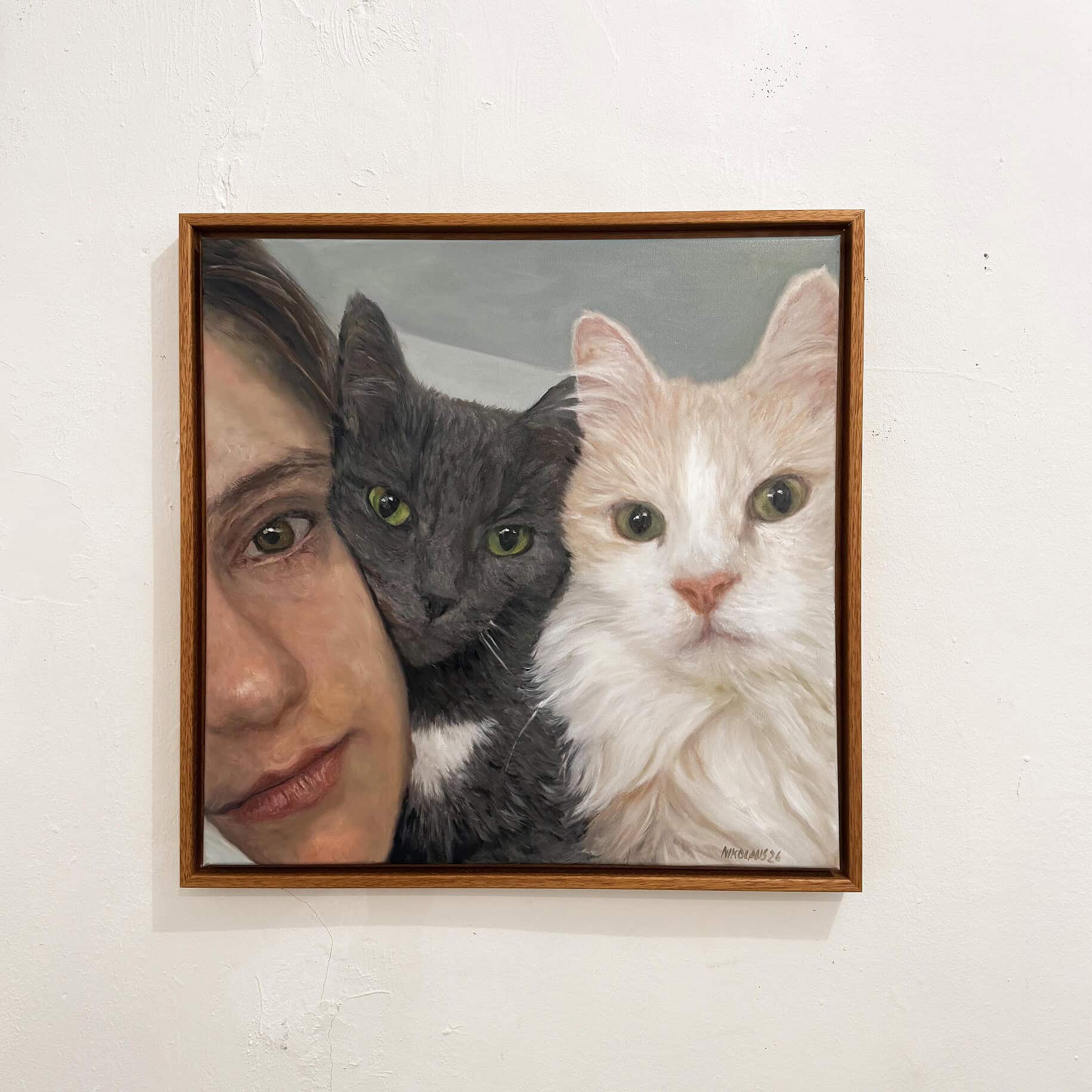 Kunstwerk mit Mensch und zwei Katzen Animal painting - Oil painting of a half-length portrait of a woman with two cats—one gray and one cream-colored—standing close together, looking straight ahead, in a wooden frame against a light-colored wall